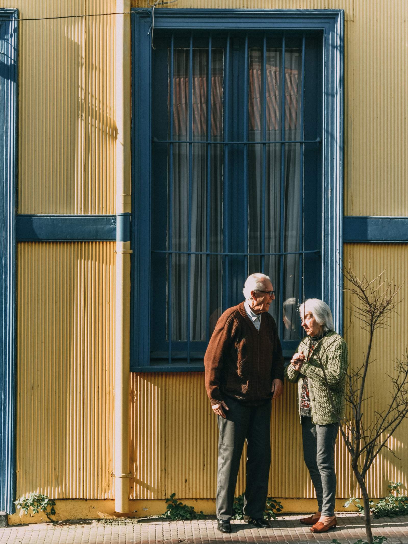 Pareja de adultos mayores conversando frente a una casa en Valparaíso