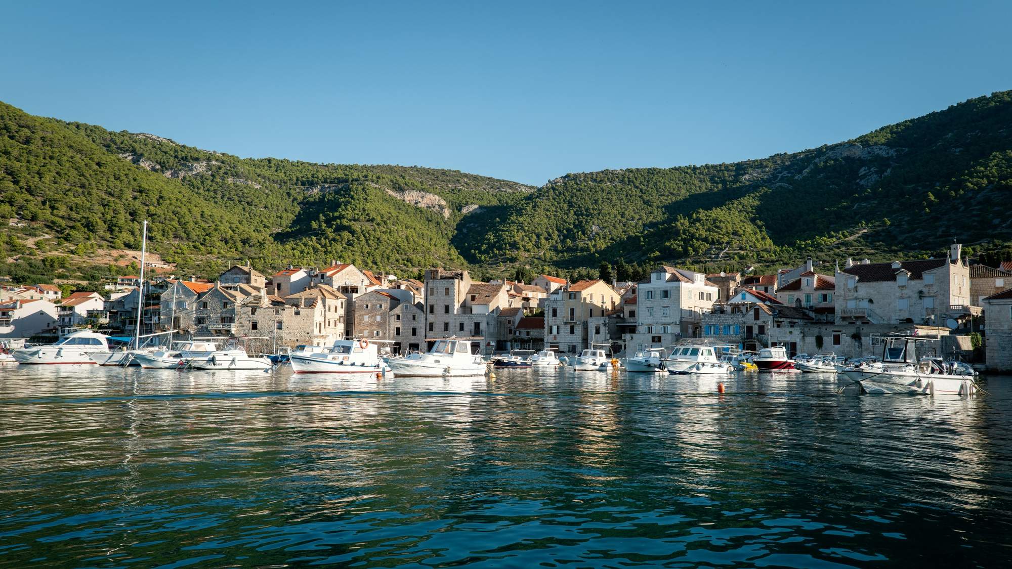 Casas de piedra y botes en el puerto de Komiža, isla de Vis, Croacia