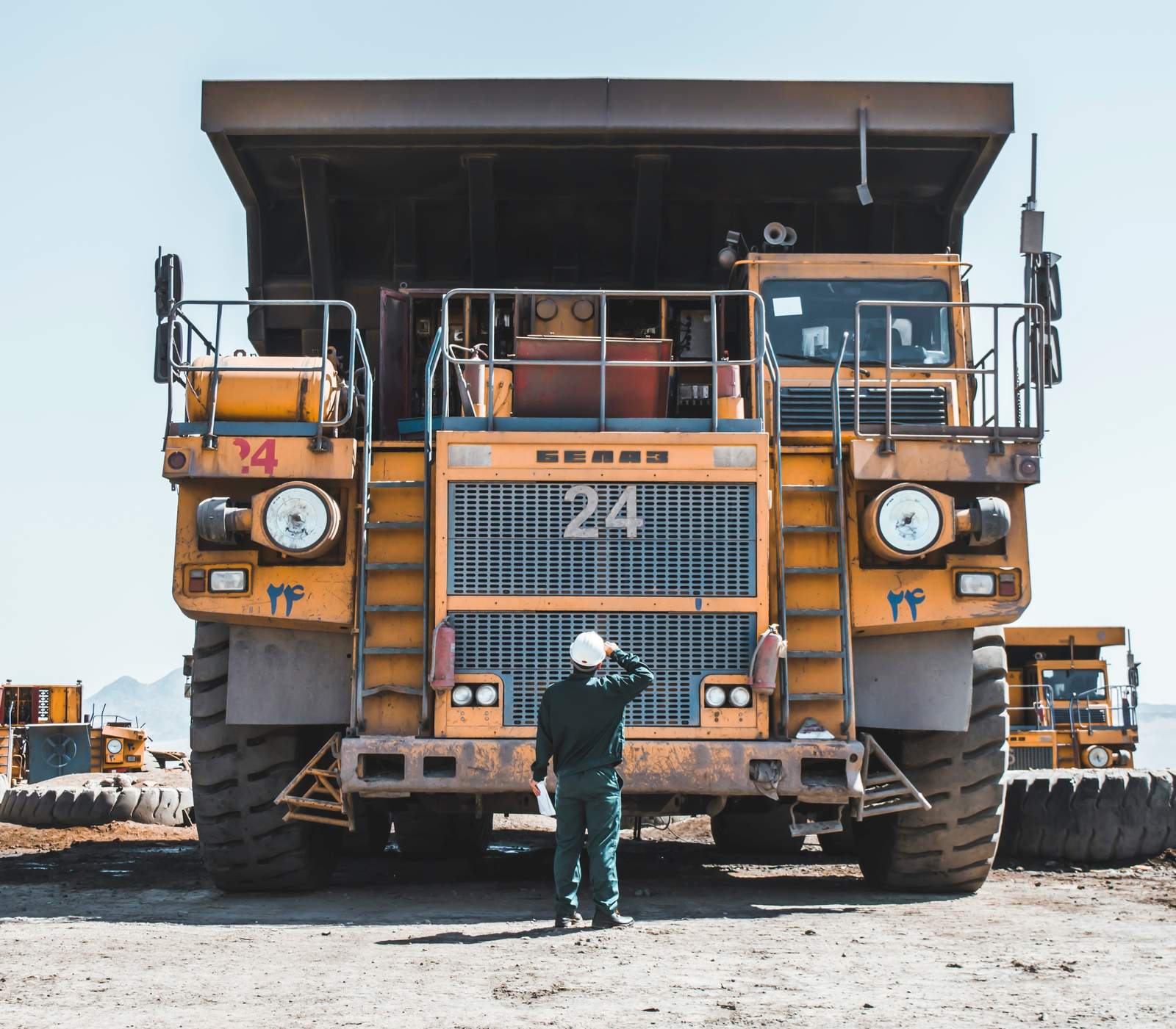 Trabajador con casco frente a un camión minero